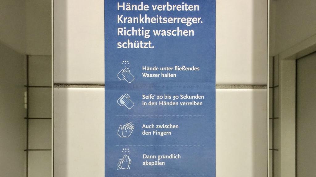 Wochenrueckblick kw 04 2026 - Schild an einer Wand, das Anweisungen zum Händewaschen mit Illustrationen enthält, geschrieben auf Deutsch; die Schritte umfassen das Halten der Hände unter fließendem Wasser, das Aufschäumen mit Seife für 20-30 Sekunden, das Waschen zwischen den Fingern und das gründliche Abspülen.