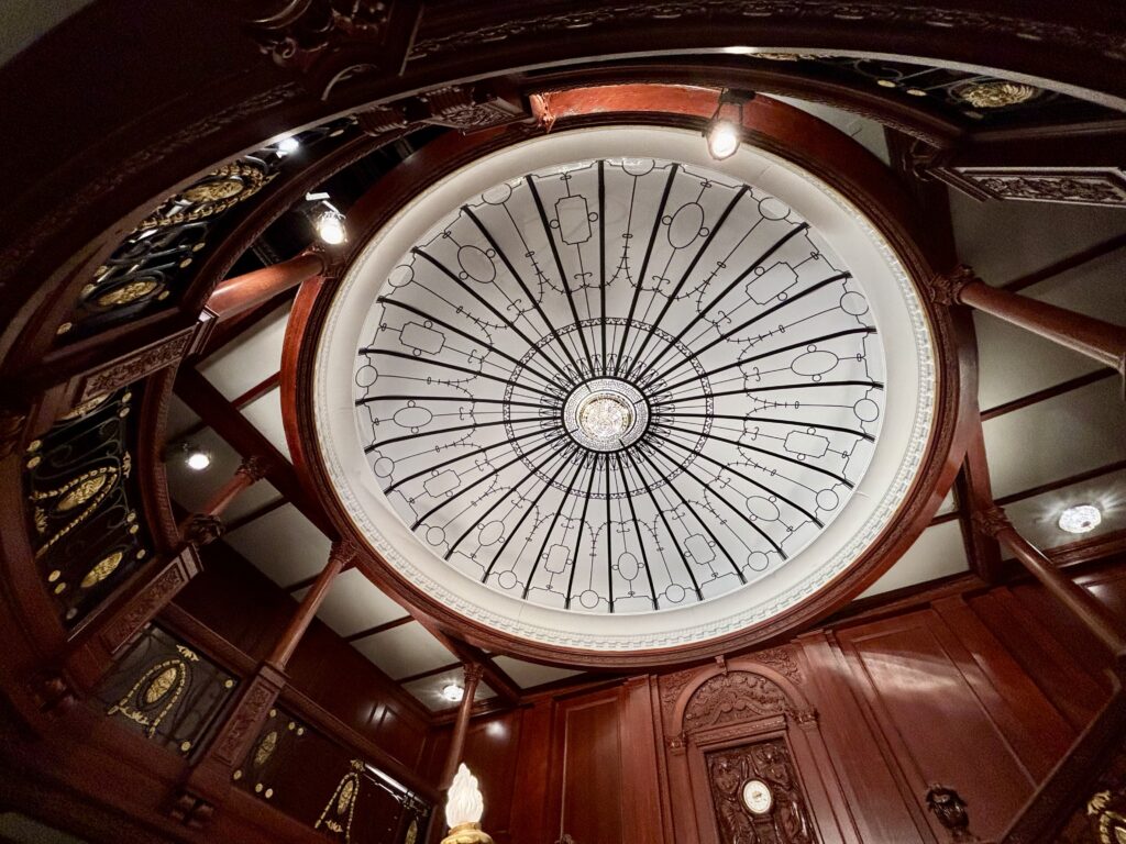 Wochenrueckblick kw 09 2026 titanic und meatballs - Eine Aufsichtsperspektive einer Rotunden-Decke mit einem kreisförmigen Glasfenster, das mit komplizierten schwarzen Linien verziert ist, umgeben von aufwendigen, dunklen Holzpaneelen und architektonischen Details.