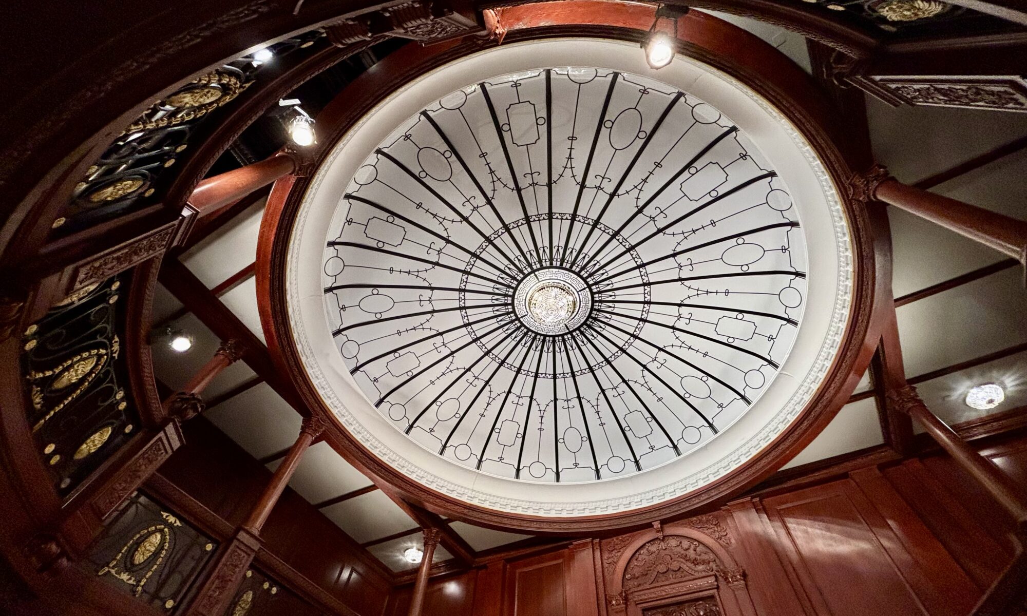 Wochenrueckblick kw 09 2026 titanic und meatballs - Eine Aufsichtsperspektive einer Rotunden-Decke mit einem kreisförmigen Glasfenster, das mit komplizierten schwarzen Linien verziert ist, umgeben von aufwendigen, dunklen Holzpaneelen und architektonischen Details.