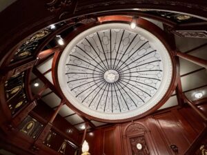 Wochenrueckblick kw 09 2026 titanic und meatballs - Eine Aufsichtsperspektive einer Rotunden-Decke mit einem kreisförmigen Glasfenster, das mit komplizierten schwarzen Linien verziert ist, umgeben von aufwendigen, dunklen Holzpaneelen und architektonischen Details.