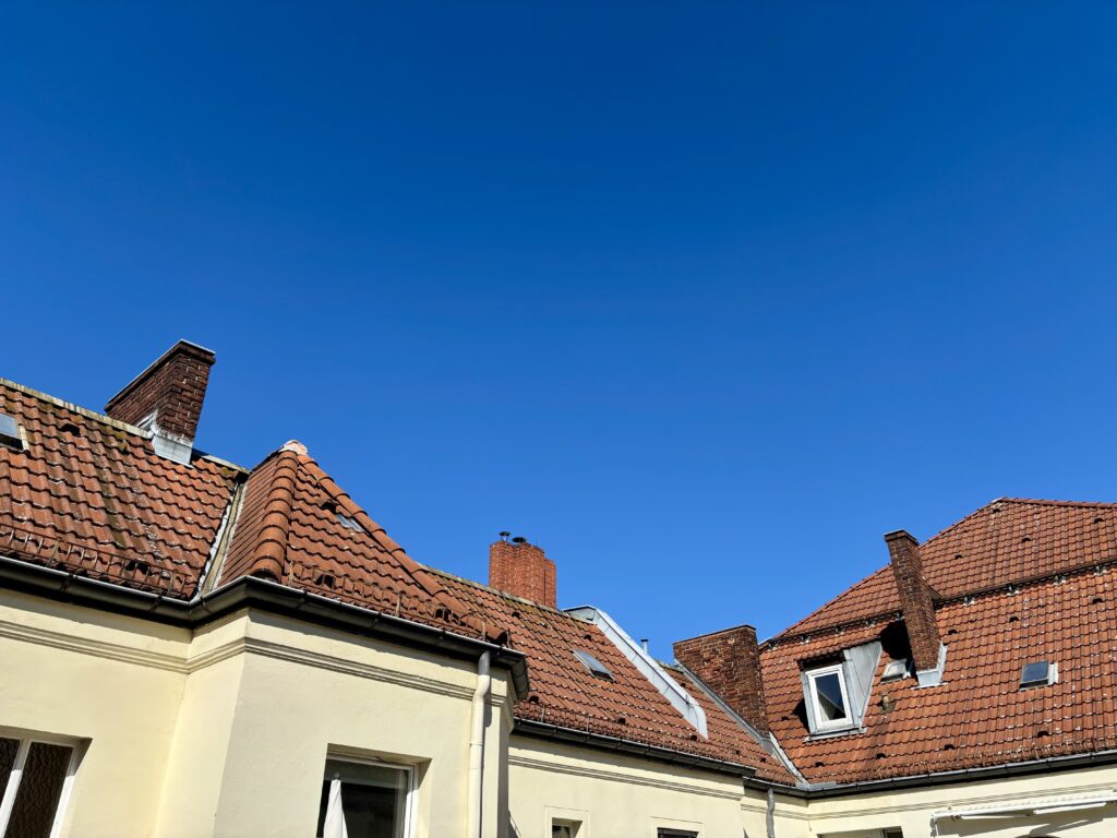 Wochenrueckblick kw 17 2026 blue screen - Tiled roofs and chimneys of residential buildings against a clear blue sky. Ziegeldächer und Schornsteine von Wohngebäuden vor einem klaren blauen Himmel.